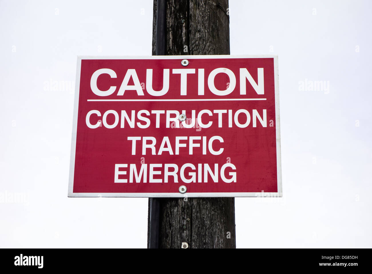 A sign  / notice on a pole - Caution, Construction traffic emerging Stock Photo