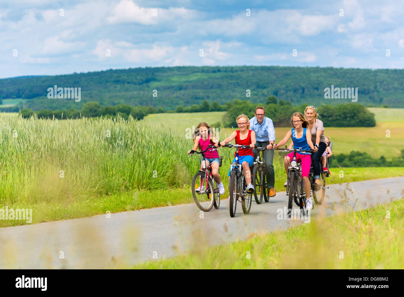 Family with three girls having a weekend excursion on their bikes on a summer day in beautiful landscape Stock Photo