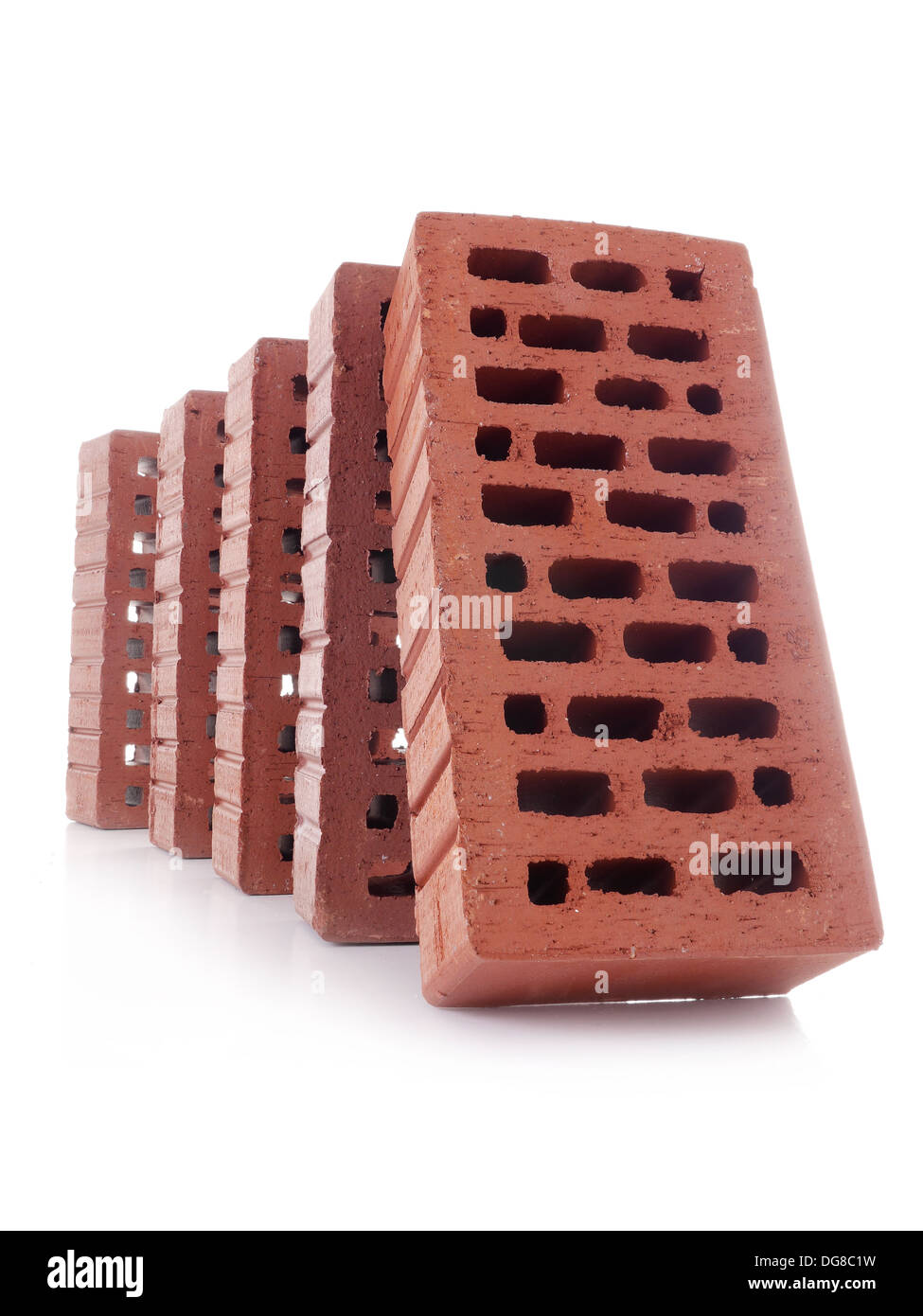 Line of red bricks with the first brick falling over the next one making a domino effect shot over white Stock Photo