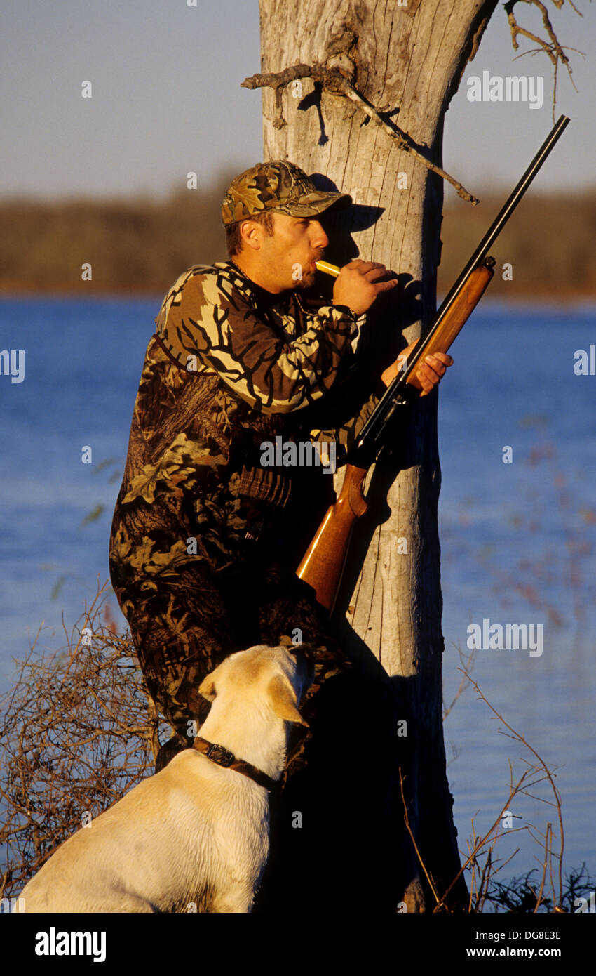 A duck hunter calling ducks with his yellow Labrador retriever hunting