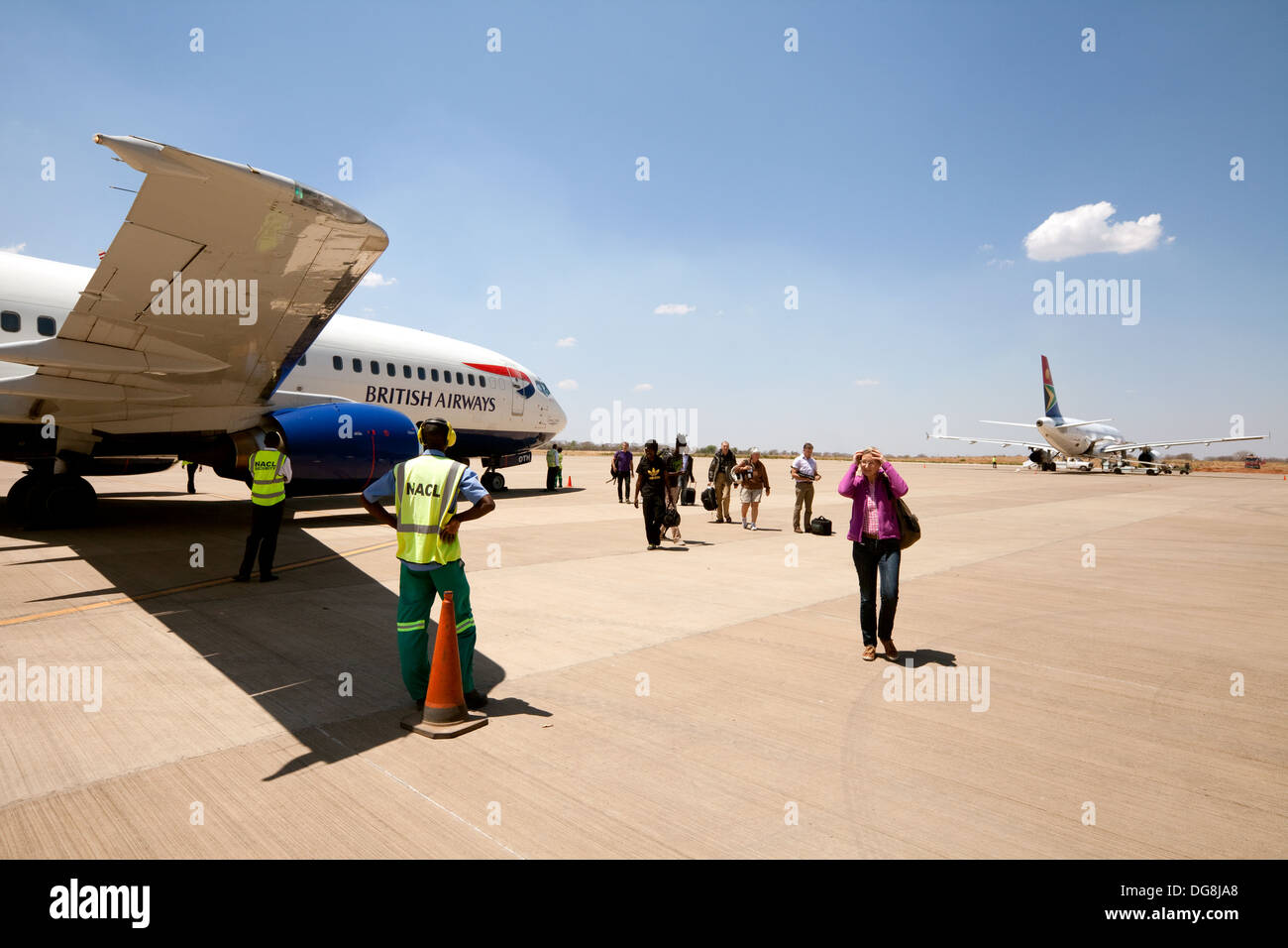 People disembarking from a British Airways Boeing 737 on the tarmac at Livingstone airport, Zambia, Africa Stock Photo
