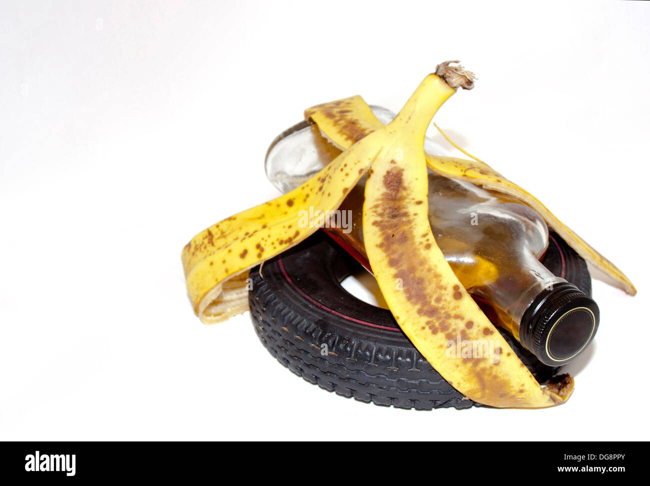 No drinking and driving concept with slippery banana peel holding together alcohol bottle an vehicle tire Stock Photo