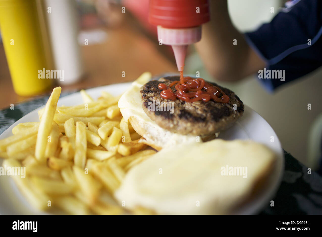 Child putting ketchup on a Hamburger Stock Photo Alamy