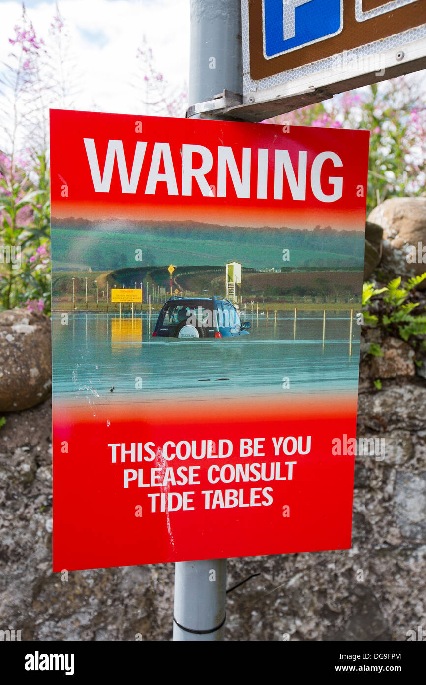 A warning sign about the causeway to Lindisfarne, or Holy Island, that floods with the tide. Stock Photo