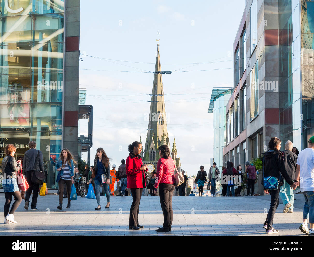 People socialising in the Bullring Centre with St Martin's Church behind, Birmingham, Midlands, England Stock Photo