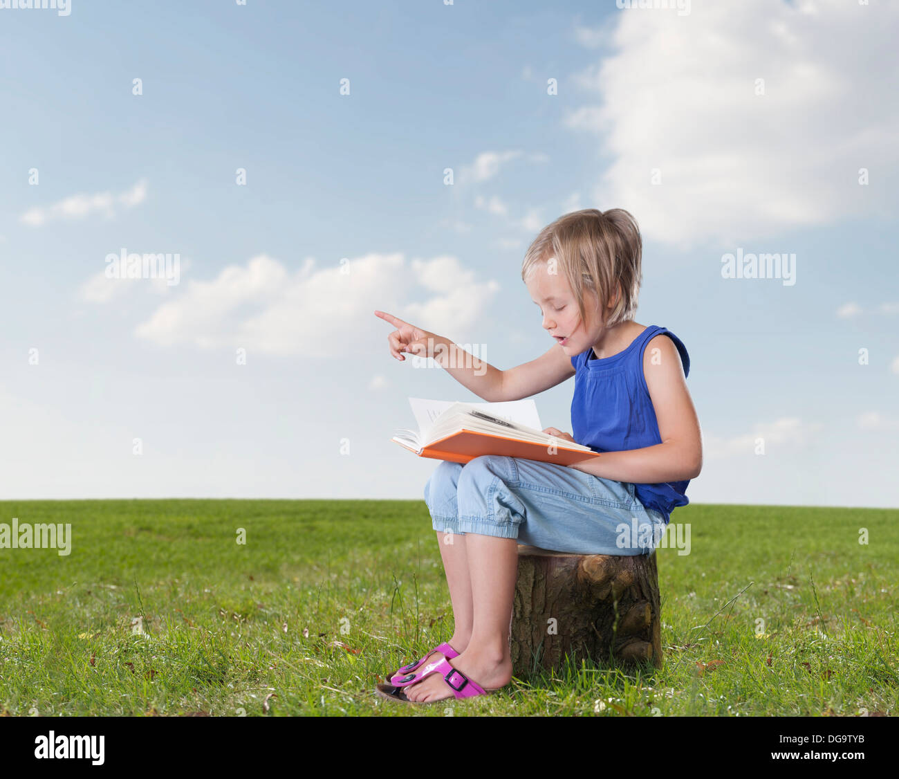 little girl with a book telling a story, outdoors Stock Photo