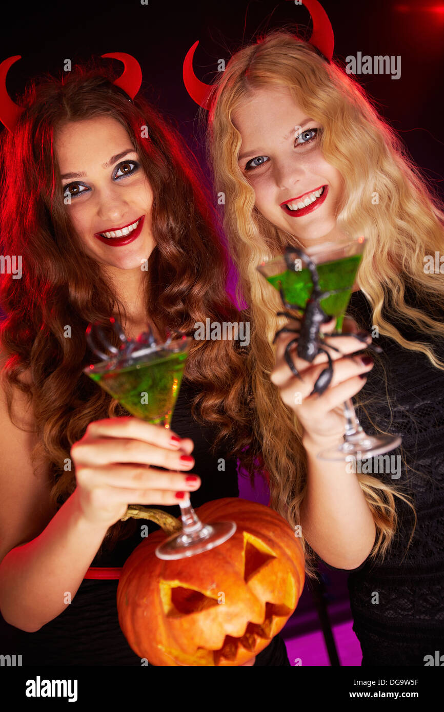 Photo of smiling females holding Halloween pumpkin and cocktails with scorpions Stock Photo