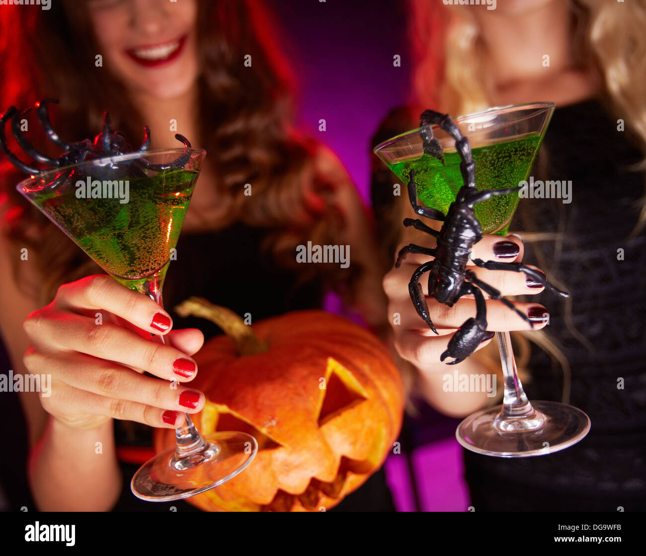 Photo of carved Halloween pumpkin and cocktails with scorpions held by females Stock Photo