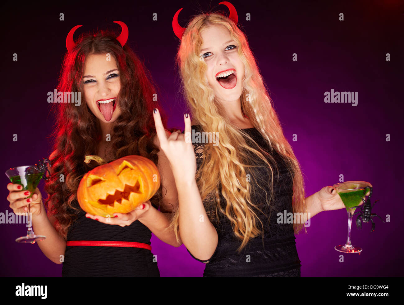 Photo of two young females with Halloween pumpkin and cocktails with scorpions having fun Stock Photo