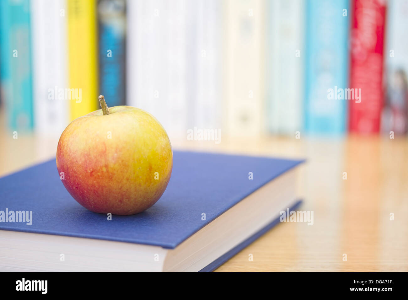 Book with ripe apple a nd row of books in background Stock Photo