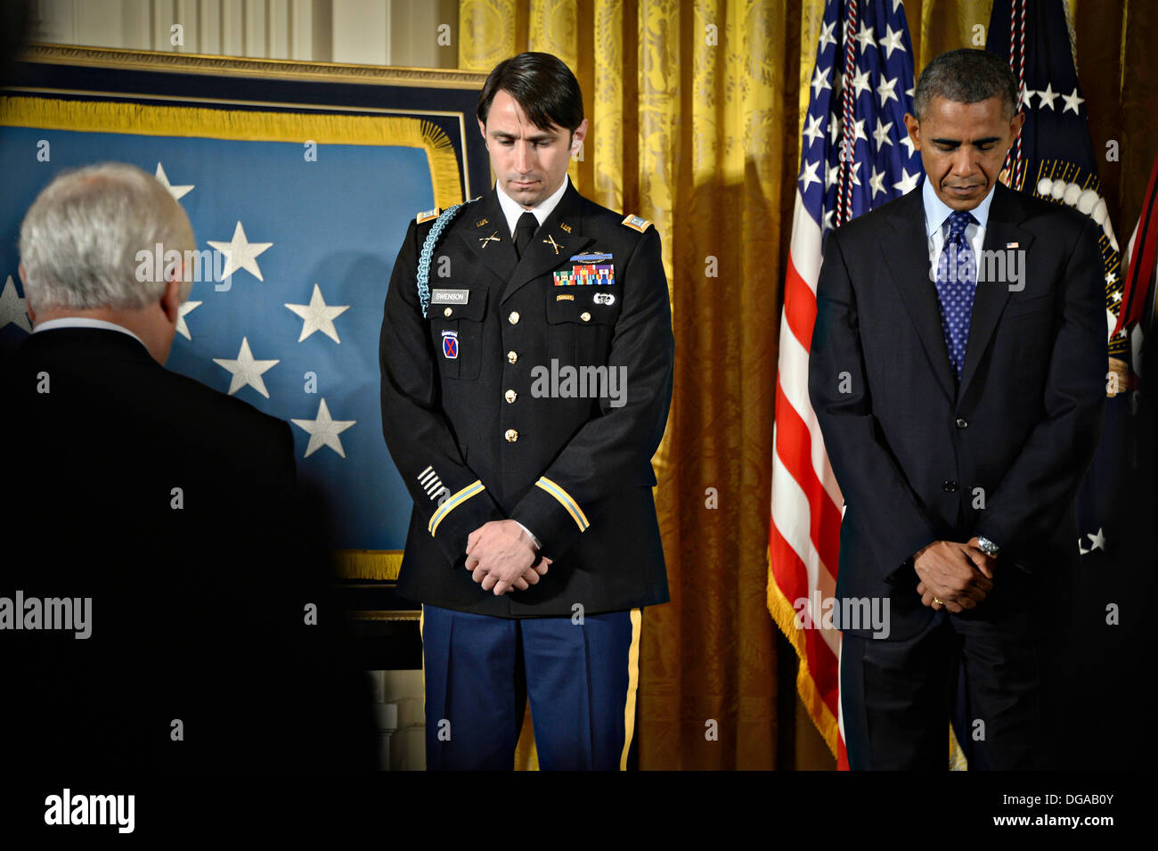 US President Barack Obama and former US Army Capt. William D. Swenson stand for a moment of silence during the Medal of Honor ceremony in the East Room of the White House October 15, 2013 in Washington, DC. The Medal of Honor is the nation's highest military honor. Stock Photo