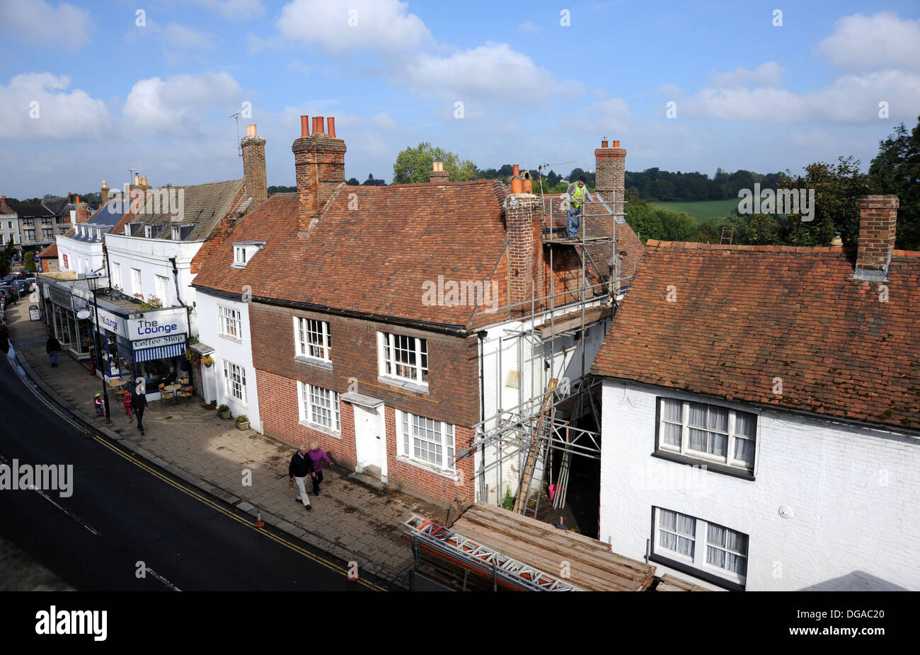Builders working on scaffolding repairing roof on old historic house in