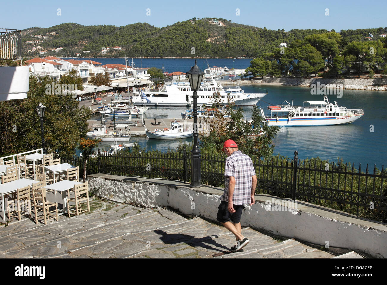 An elderly tourist walking down the steps leading to the Old Port in Skiathos Town on the Greek Island of Skiathos in the Aegean Stock Photo