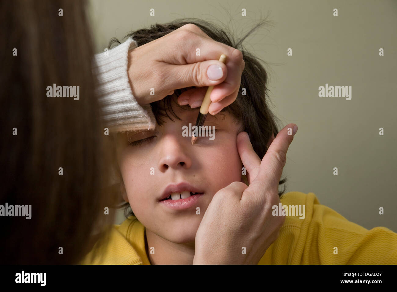 Woman putting theatrical makeup on a boy´s face Stock Photo 61695395