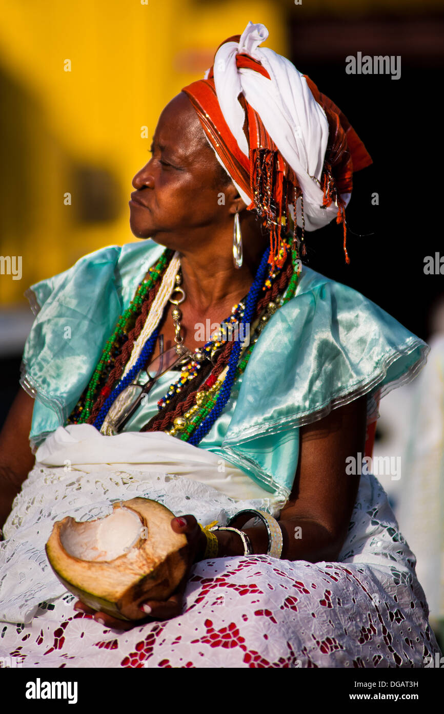 A Baiana woman, eating a coconut, seen in front of the St. Lazarus church in Salvador, Bahia, Brazil. Stock Photo