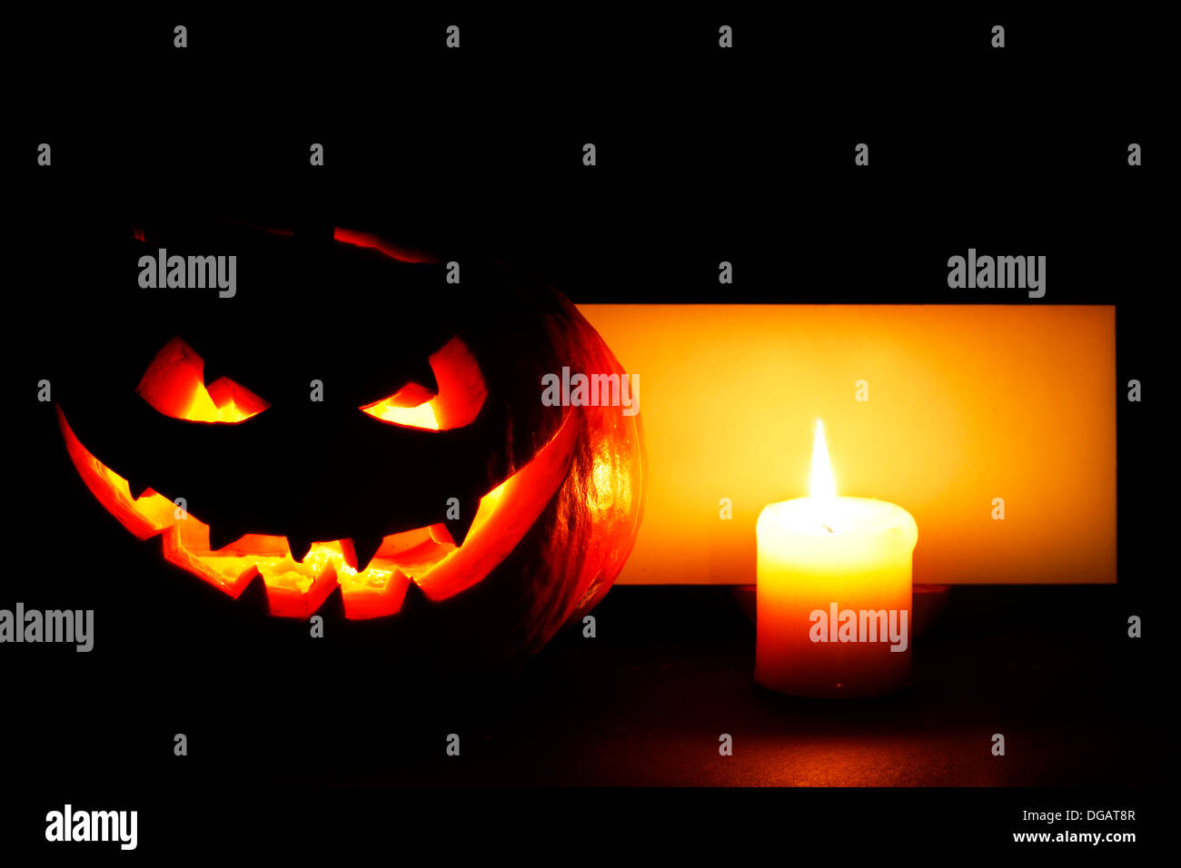 Halloween pumpkin with burning candle and post card on black background ...