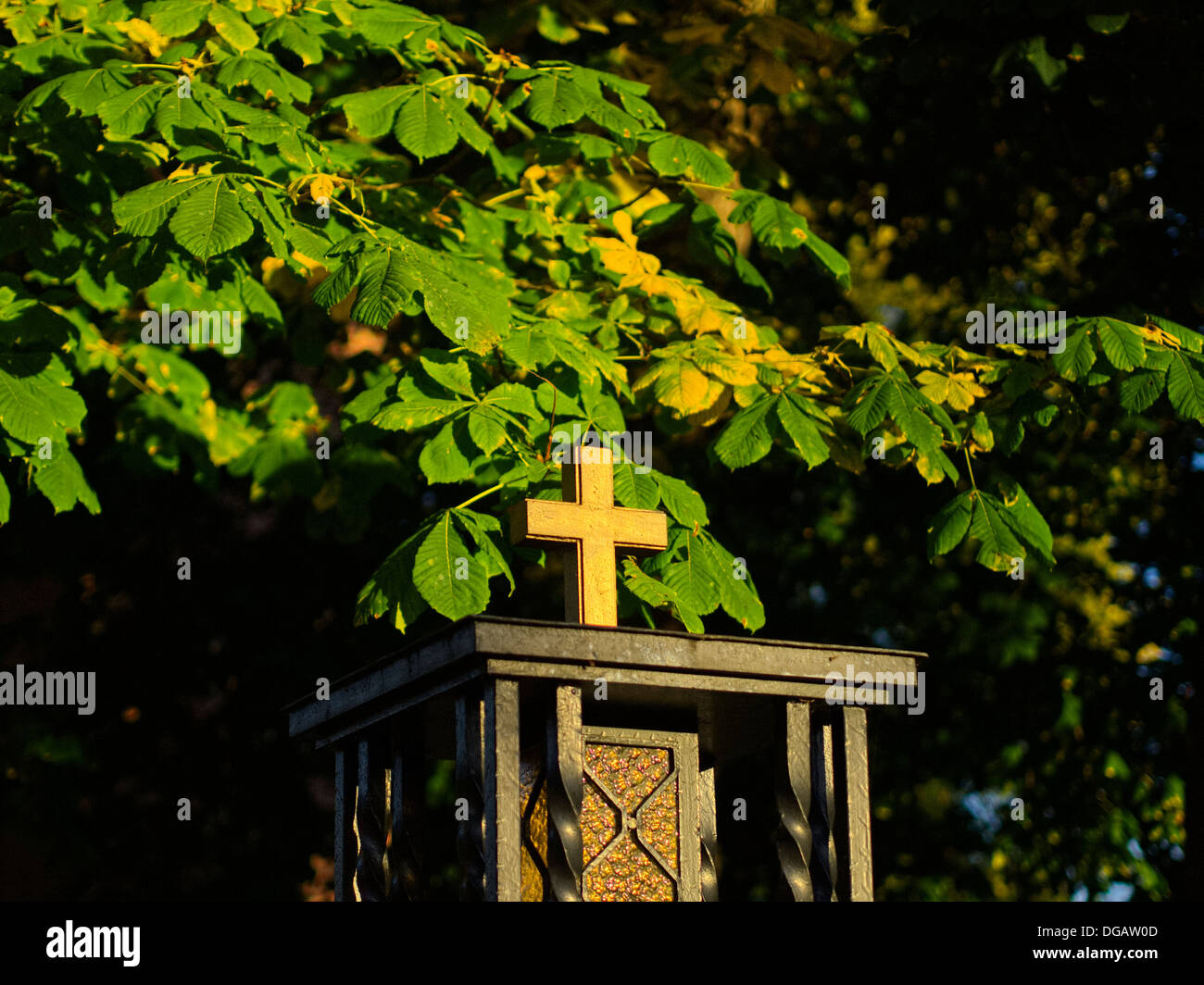 cross radiating in evening sun, autumnal foliage Stock Photo