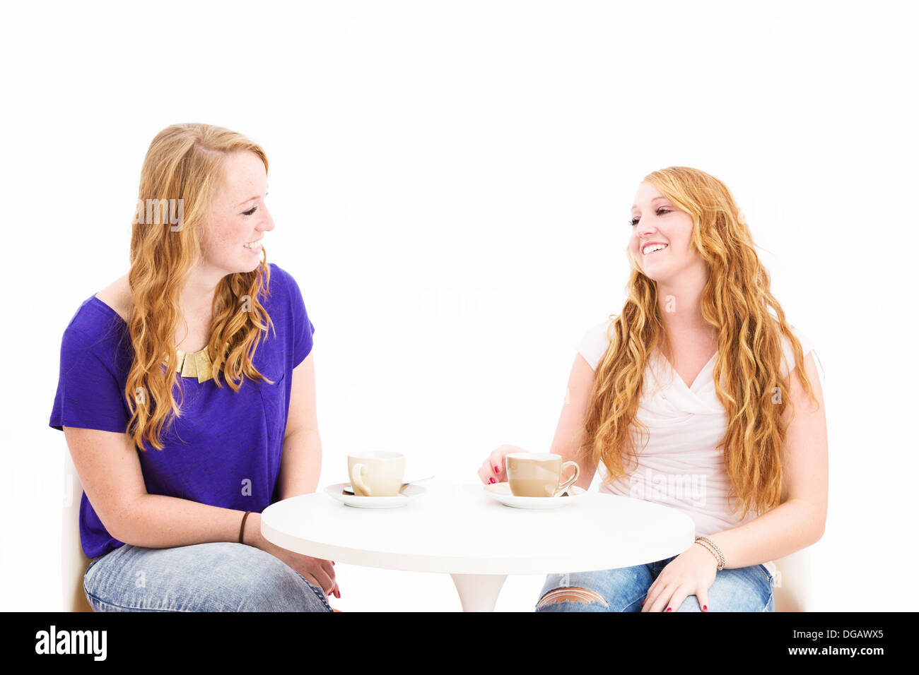 happy chatting women sitting at a coffee table on white background Stock Photo