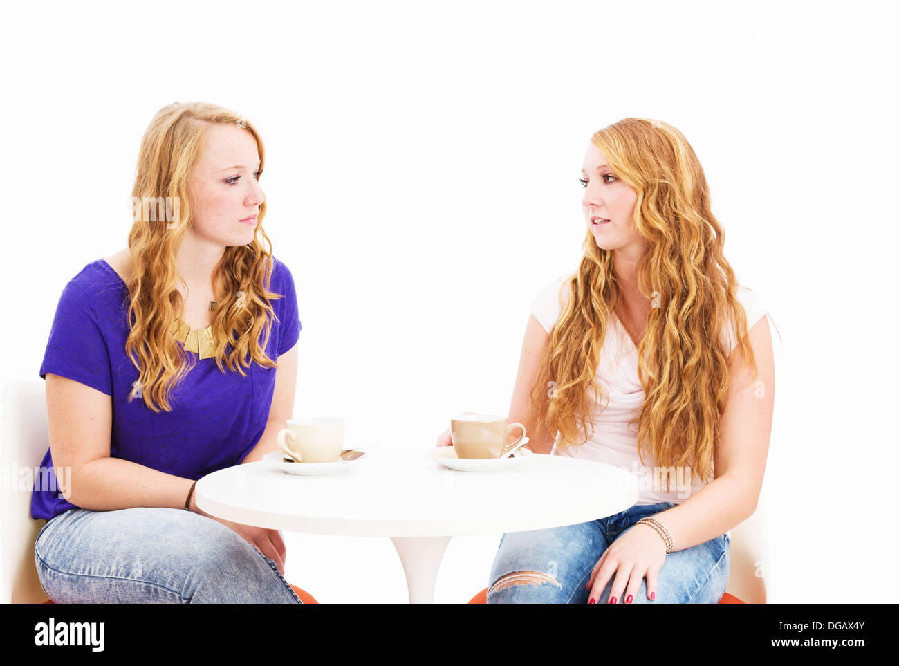 serious talking women sitting at a coffee table on white background Stock Photo