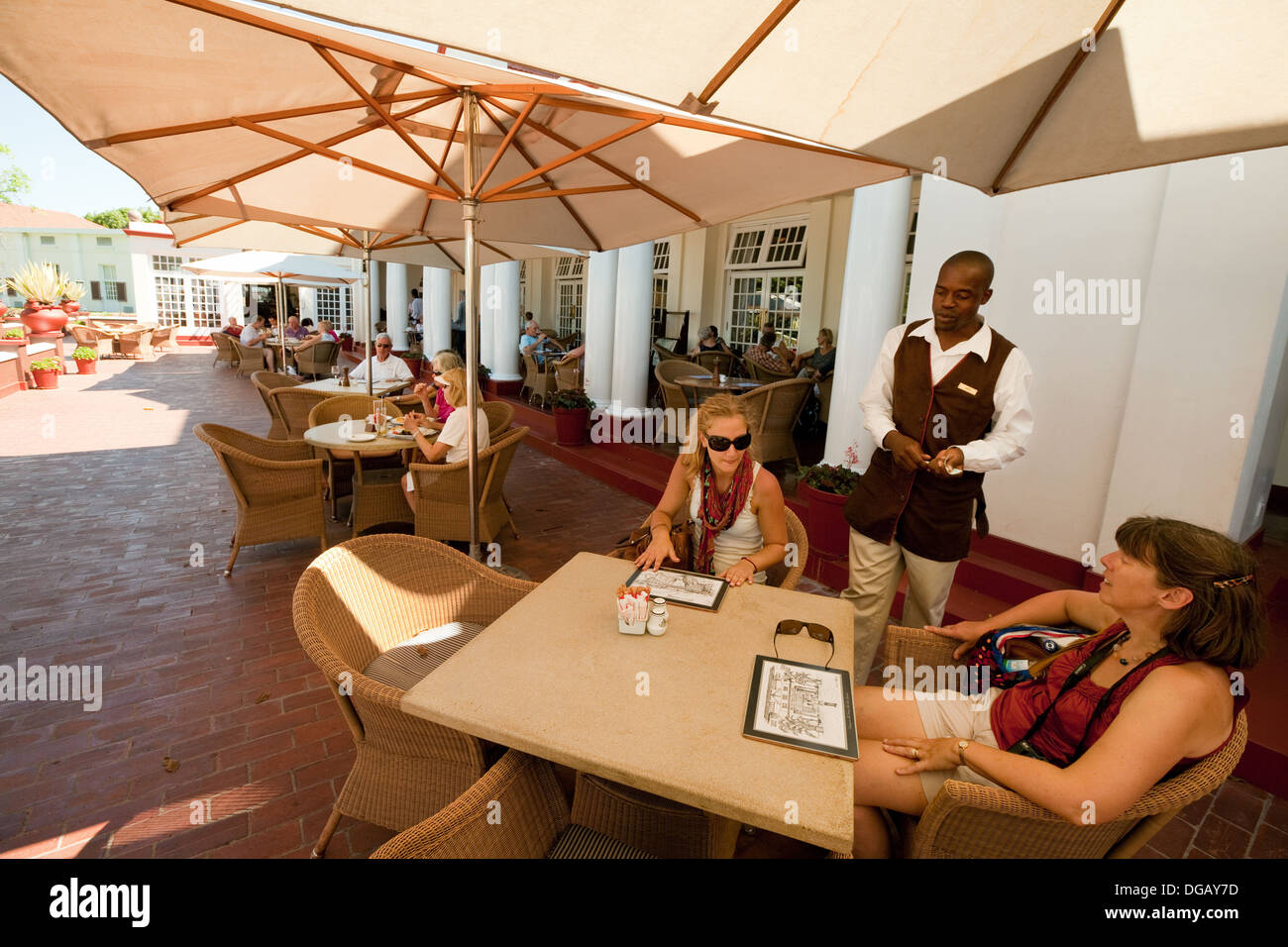 Guests ordering tea from the waiter, the veranda of the 5 star Victoria Falls Hotel, Zimbabwe Africa Stock Photo