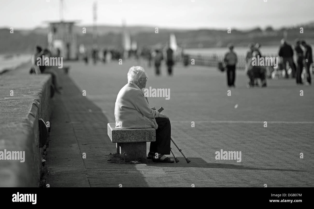 old lady alone Mountbatten Pier Plymouth sitting with walking sticks in Black and white Stock Photo