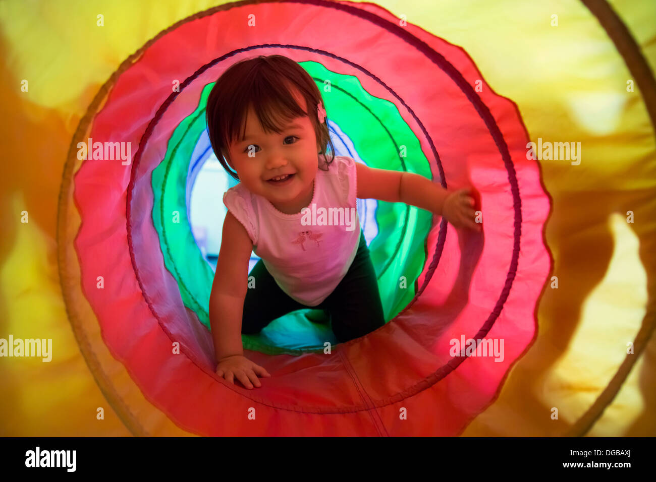 Baby girl crawling through play tunnel Stock Photo