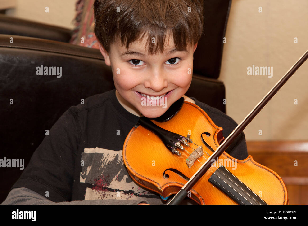 Happy boy age 8 playing violin in his home. St Paul Minnesota MN USA Stock Photo