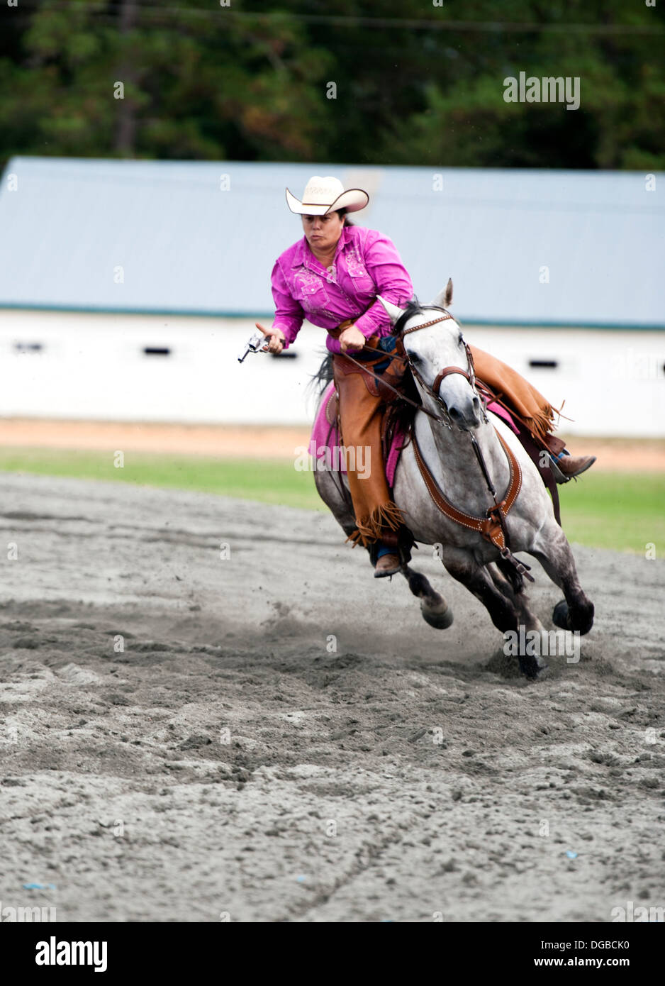 A cowgirl on a horse riding at full gallop with pistol drawn. Annie Oakley Boom Days Festival in Pinehurst North Carolina. Stock Photo