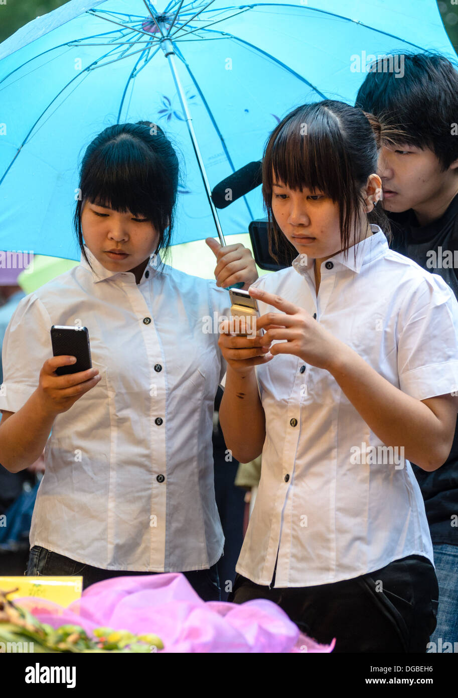 Young ladies in office uniform check their mobile phones Stock Photo