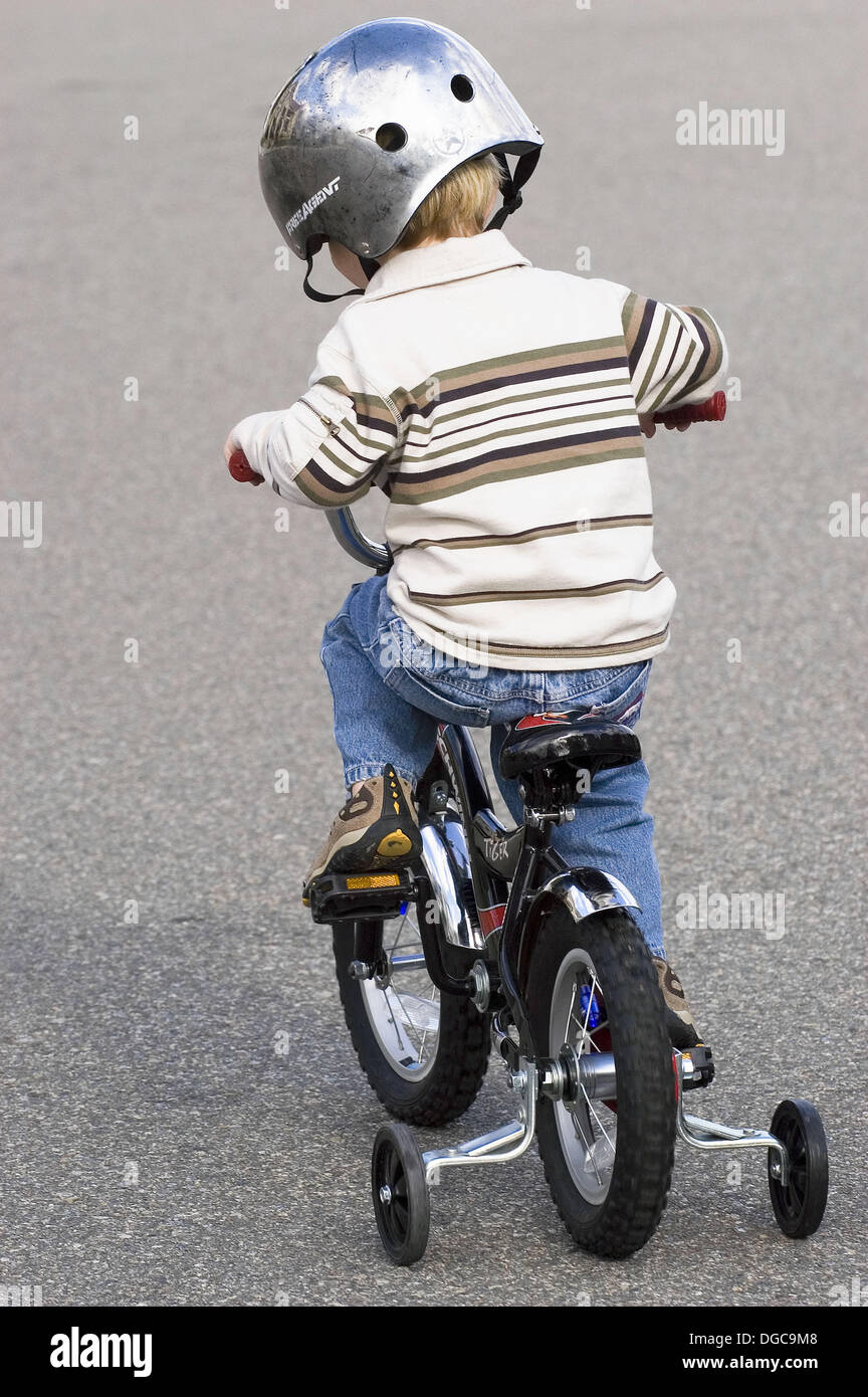 Boy riding bike with training wheels Stock Photo Alamy