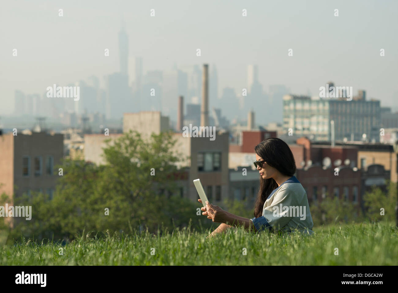 Mid adult women using digital tablet in Sunset Park with Manhattan skyline Stock Photo