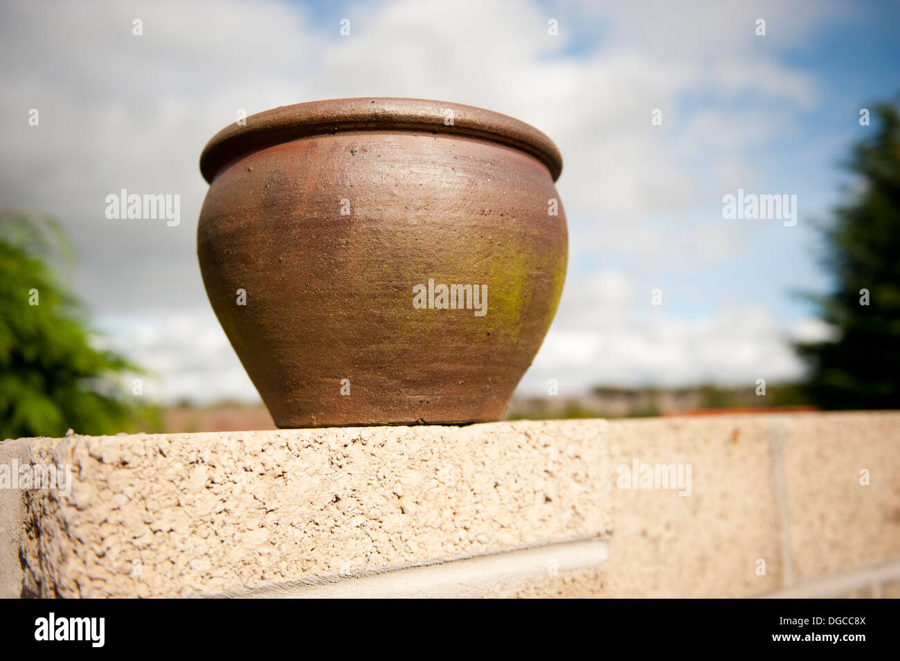 clay plant pot sitting on concrete block garden wall Stock Photo