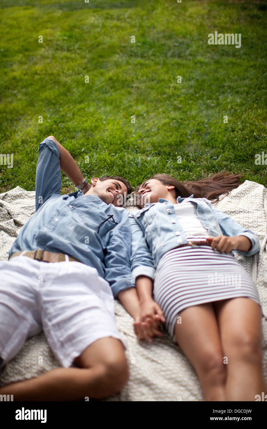 Young couple lying in park and holding hands Stock Photo
