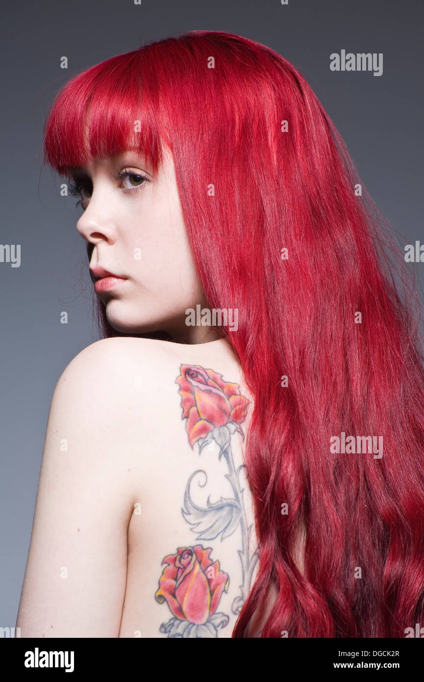 Young woman with long red hair and tattoo, studio shot Stock Photo