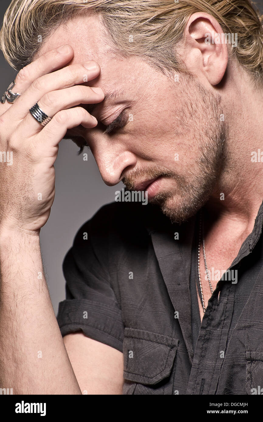 Young man with head in hands, studio shot Stock Photo