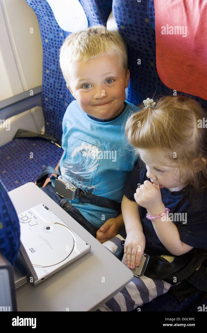 5 year old boy with little sister sitting on plane watching a dvd