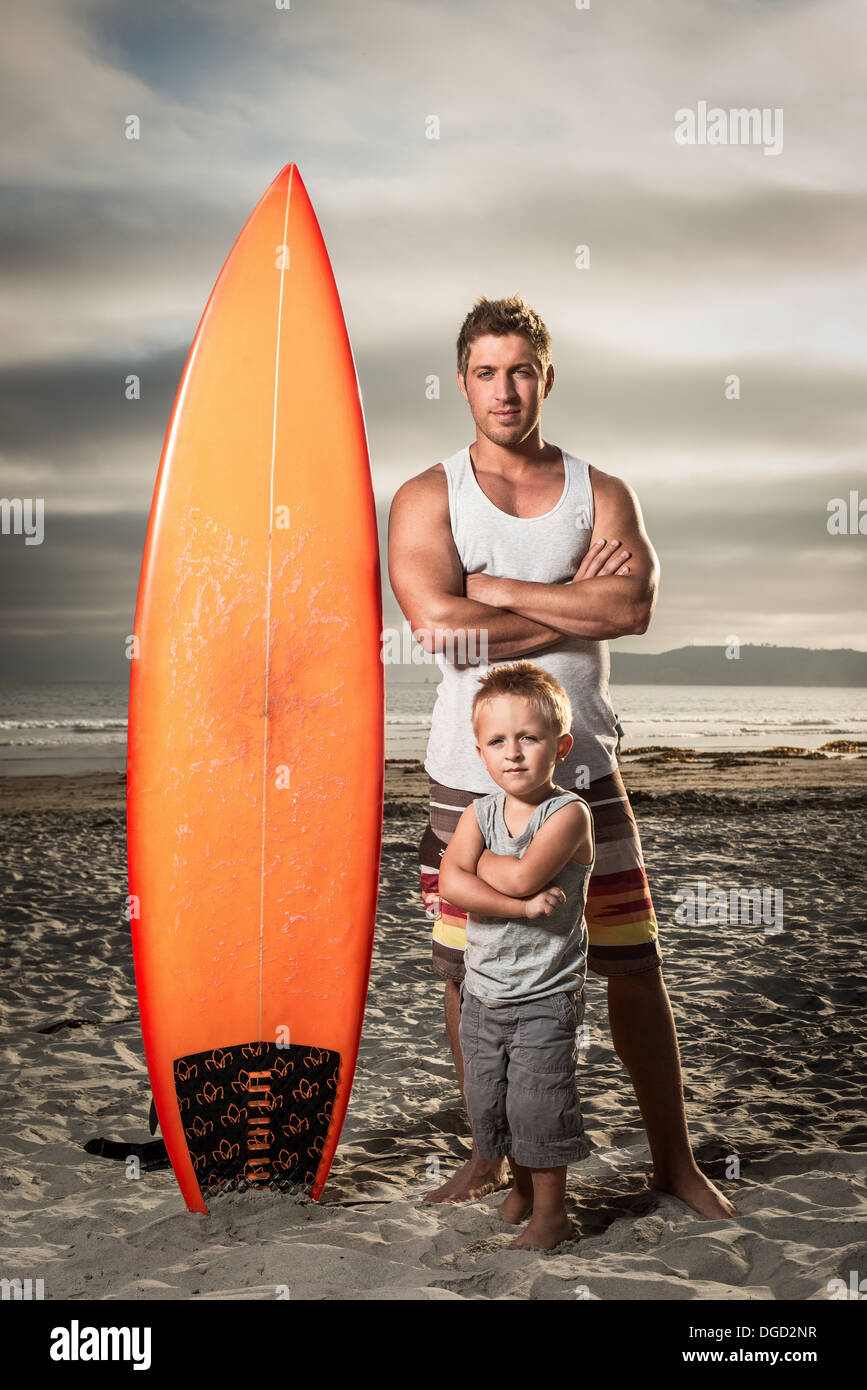 Young man and son standing with surfboard on beach, portrait Stock Photo