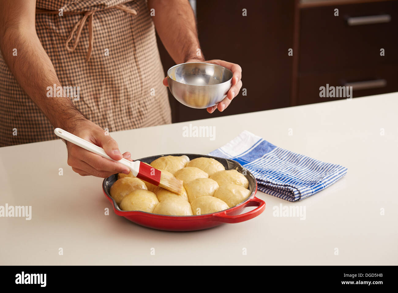 Painting raw brioche balls in a pan with egg yolk Stock Photo