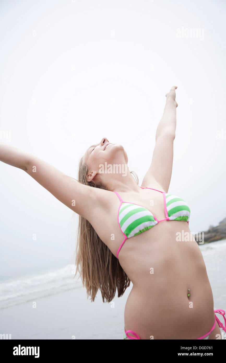 Young woman in bikini stretching on beach Stock Photo - Alamy