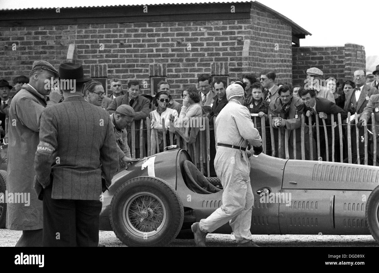 Mechanic Luigi Parenti pushes Dr Farina’s Maserati 4CLT in the assembly area at Goodwood, England 1951. Stock Photo