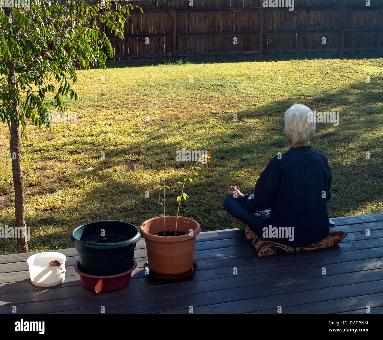 Woman in meditation in early morning in her backyard. Stock Photo