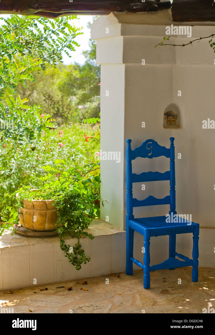 Antique Blue Wooden and Wicker Chair in a Porch and Sunlit Garden Stock Photo