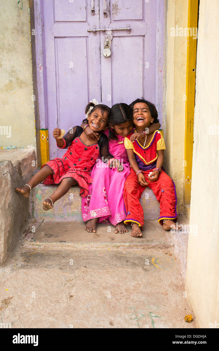 Smiling happy young rural Indian village girls sitting laughing in front of their village house. Andhra Pradesh, India Stock Photo