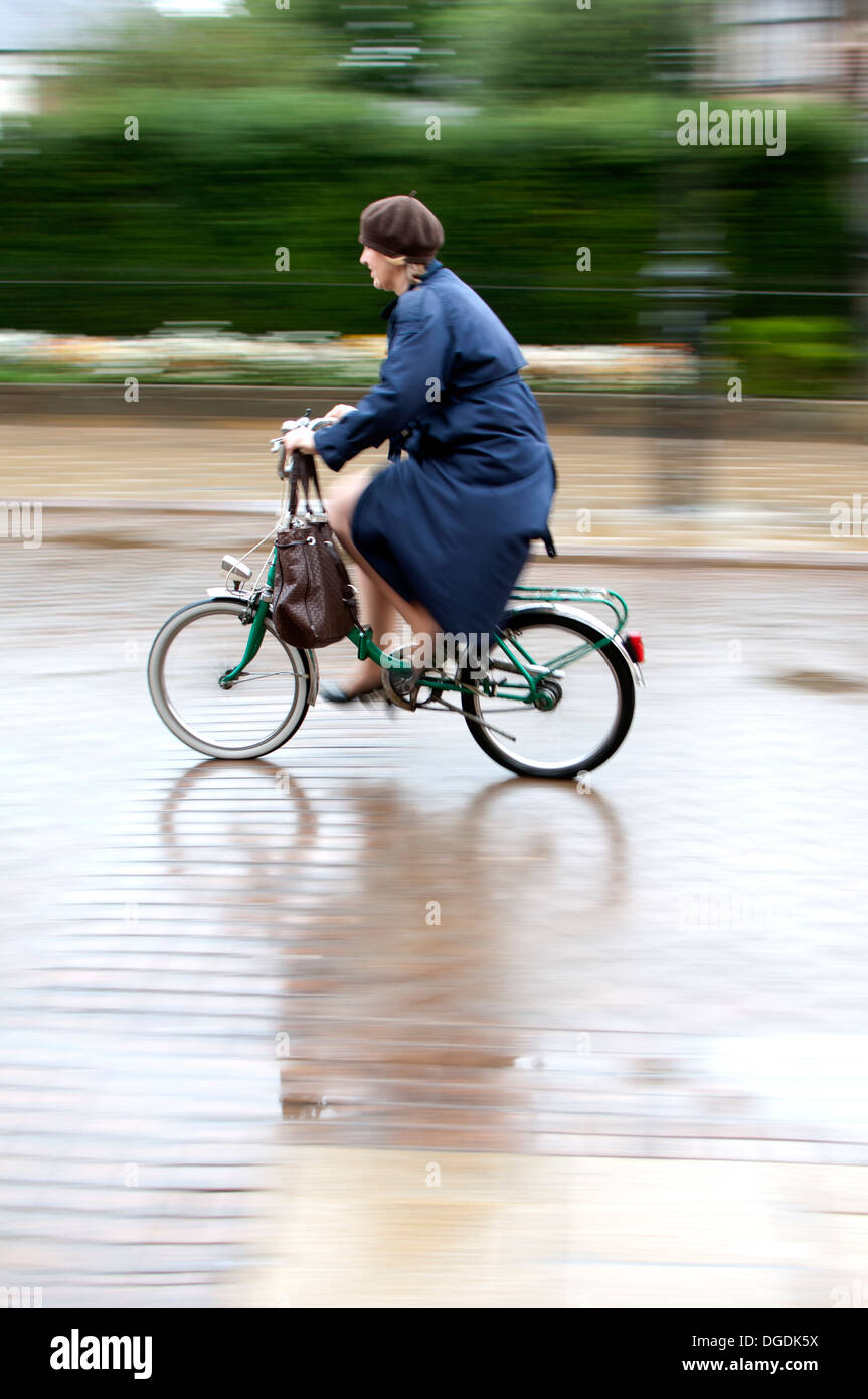 Woman cycling in wet weather Stock Photo