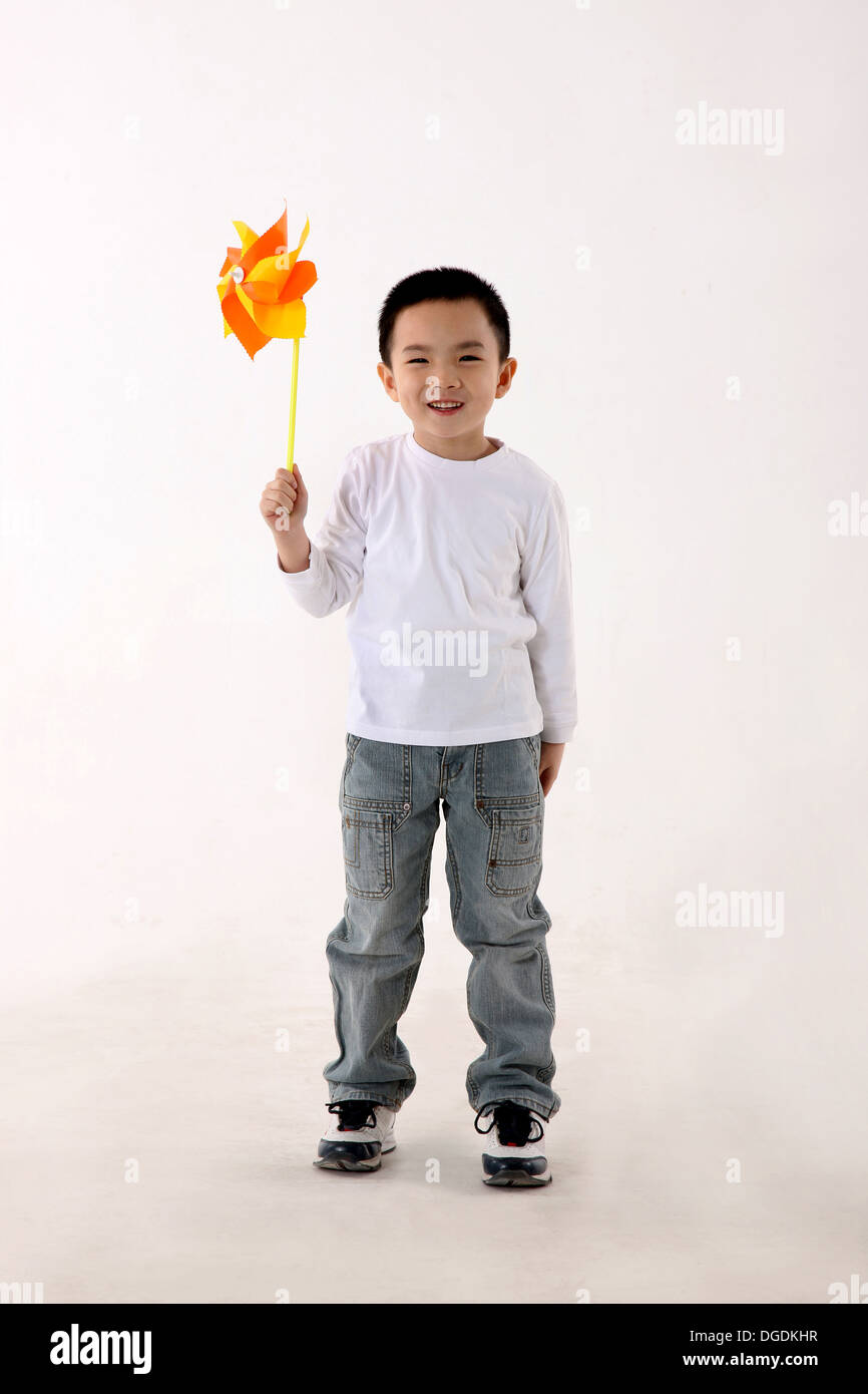 East Asian Boy Holding Paper Windmill Aloft, Smiling, Looking at Camera Stock Photo
