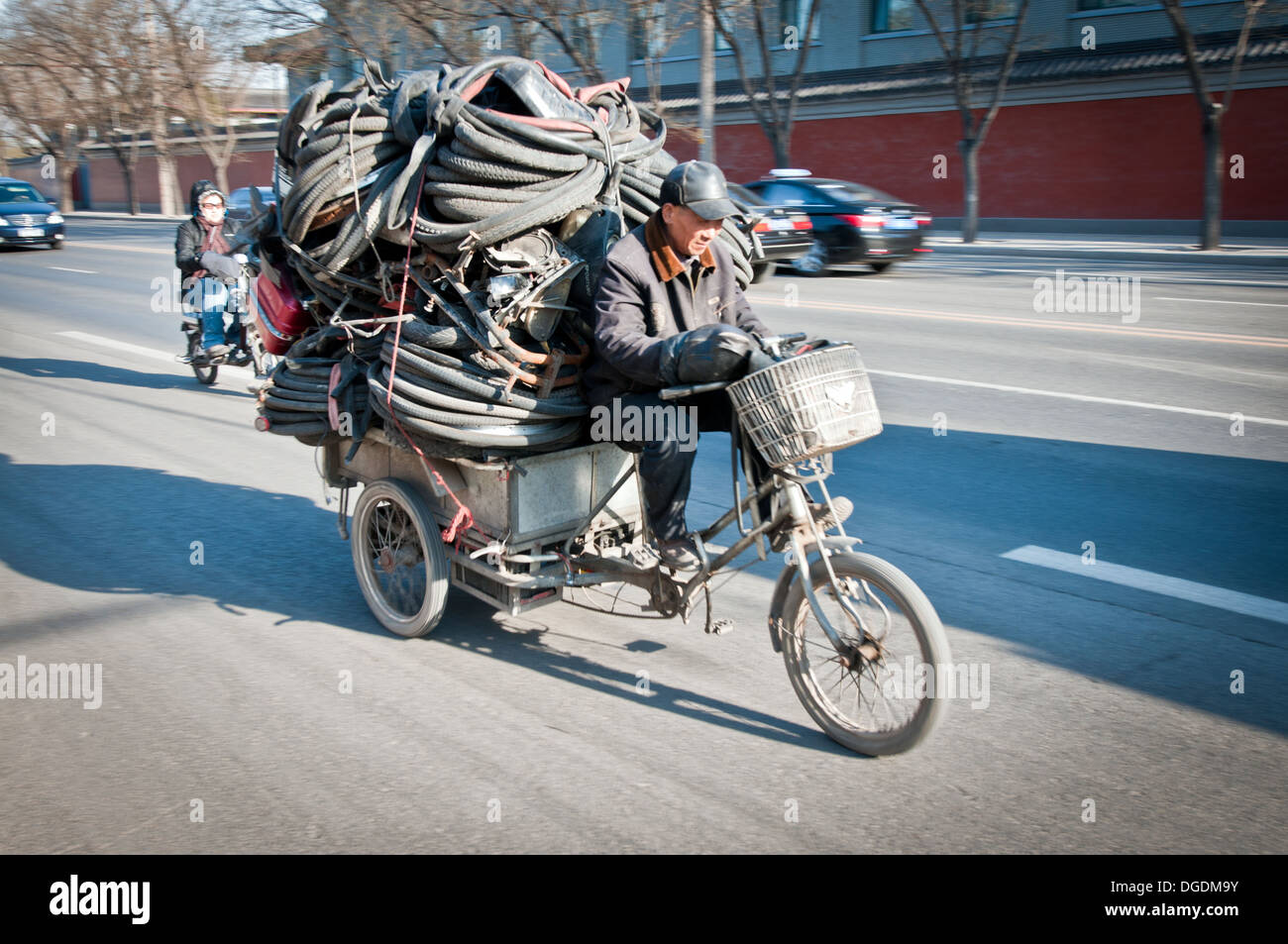 Man riding bike with cart loaded with old tires and scrap metal in Beijing, China Stock Photo