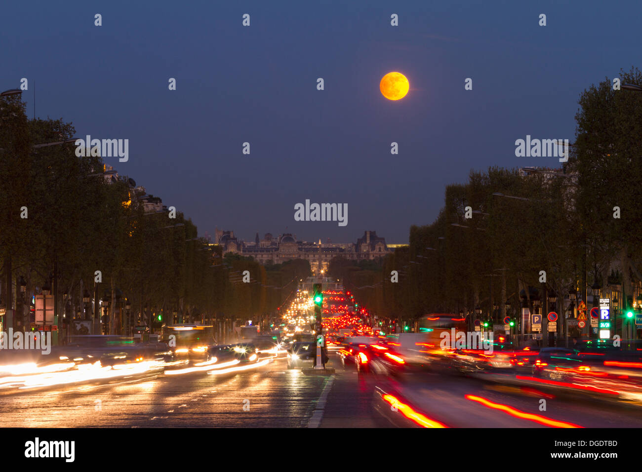 The moon rising above Avenue des Champs Elysees looking towards Louvre Paris France Stock Photo