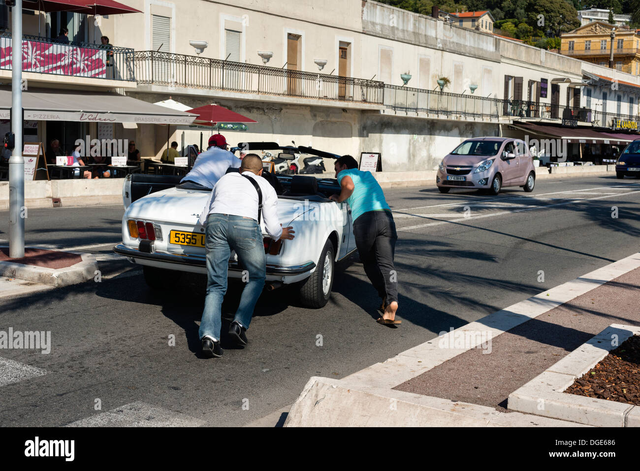 Men pushing a broken down car on Promanade des Anglais, Nice Stock Photo