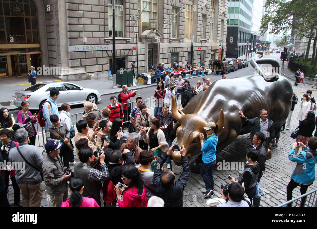 Tourists in New York City posing with the Charging Bull Sculpture near Wall Street Stock Photo Tourists in New York City posing with the Charging Bull Sculpture near Wall Street Stock Photo
