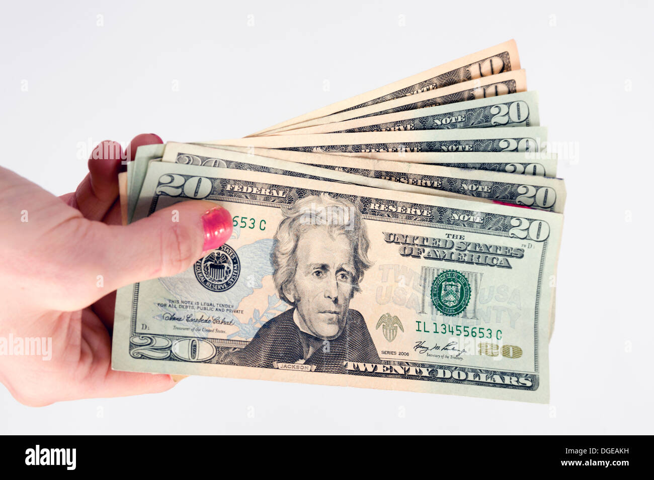 Woman holds out bills fanned out twenties and tens U.S. currency Stock Photo